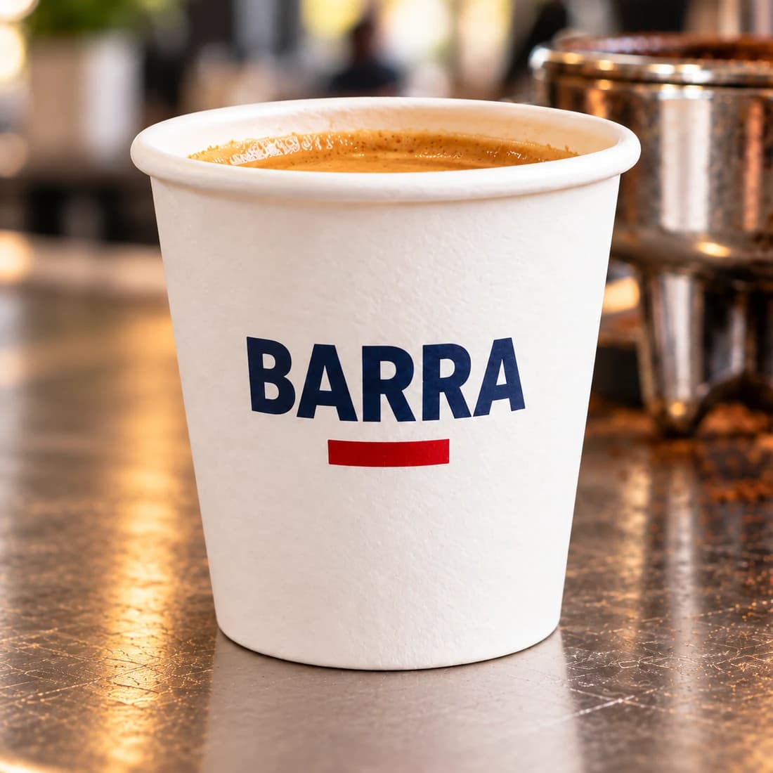 Close-up of a BARRA-branded 2 oz paper espresso cup on a café counter